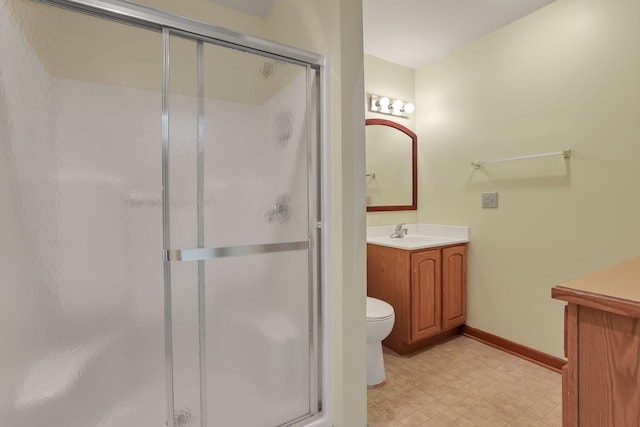 bathroom with toilet, baseboards, a shower stall, and vanity