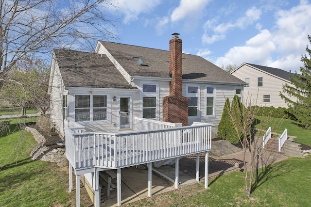 back of property with a yard, a deck, and a chimney