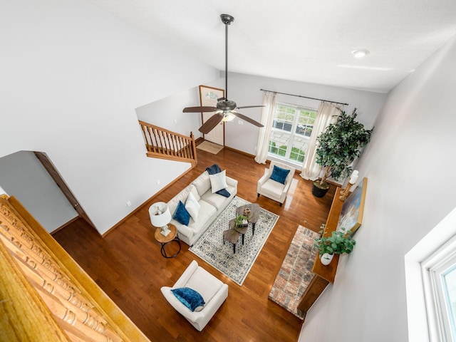 living room with ceiling fan, lofted ceiling, wood finished floors, and stairs