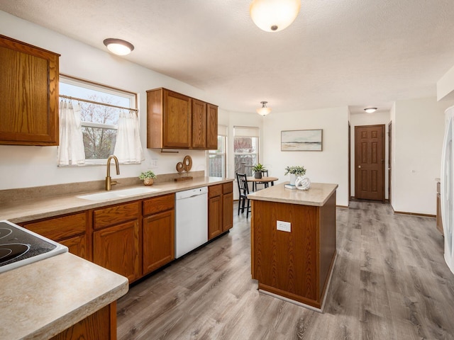 kitchen featuring a sink, white dishwasher, wood finished floors, and brown cabinets