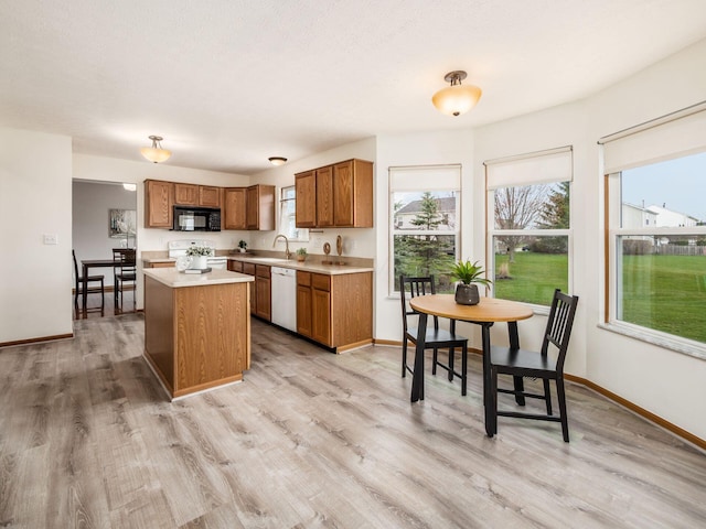 kitchen featuring black microwave, dishwasher, light countertops, brown cabinets, and stove