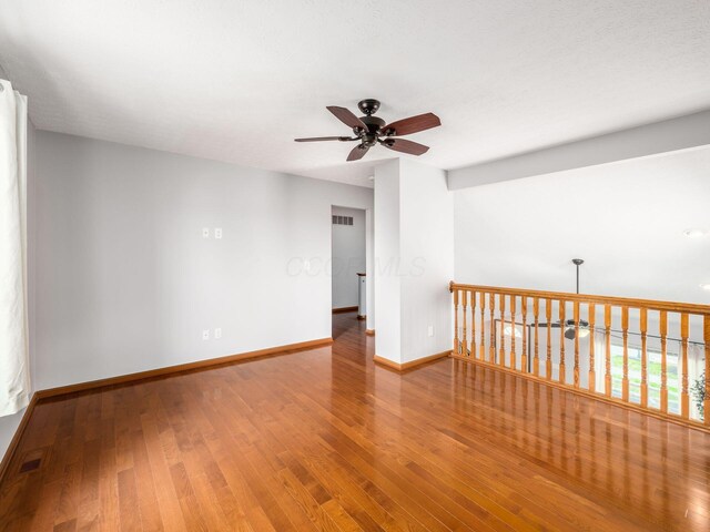 spare room featuring visible vents, ceiling fan, wood finished floors, and baseboards