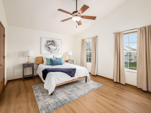 bedroom featuring ceiling fan, light wood-style flooring, baseboards, and lofted ceiling