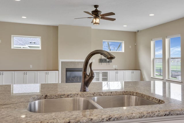 5351 Lilac Ave, Grove City, OH 43123 - kitchen view of light stone countertops, white cabinetry, recessed lighting, a glass covered fireplace, and ceiling fan