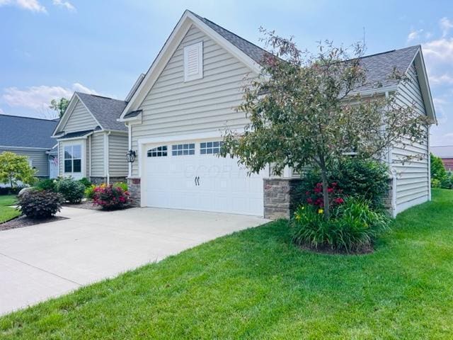 5351 Lilac Ave, Grove City, OH 43123 - view of front facade featuring driveway, a front lawn, an attached garage, roof with shingles, and stone siding