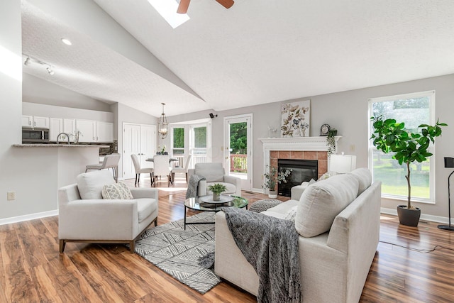 1148 Challis Springs Dr, New Albany, OH 43054 - living room with ceiling fan, lofted ceiling, wood finished floors, a tiled fireplace, and baseboards