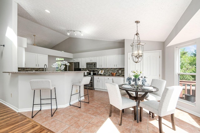 1148 Challis Springs Dr, New Albany, OH 43054 - dining room with vaulted ceiling, light tile patterned floors, baseboards, a chandelier, and a textured ceiling
