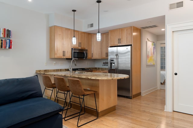 kitchen with a peninsula, appliances with stainless steel finishes, visible vents, and light brown cabinets