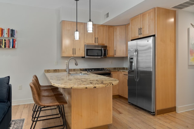 kitchen featuring visible vents, a peninsula, light brown cabinets, a sink, and appliances with stainless steel finishes
