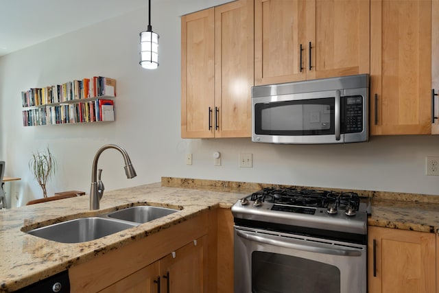 kitchen featuring appliances with stainless steel finishes, hanging light fixtures, light brown cabinetry, light stone countertops, and a sink