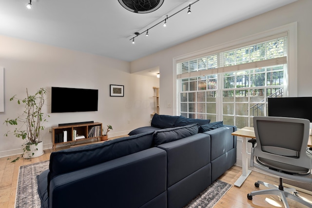 living area with baseboards, track lighting, and light wood-style flooring