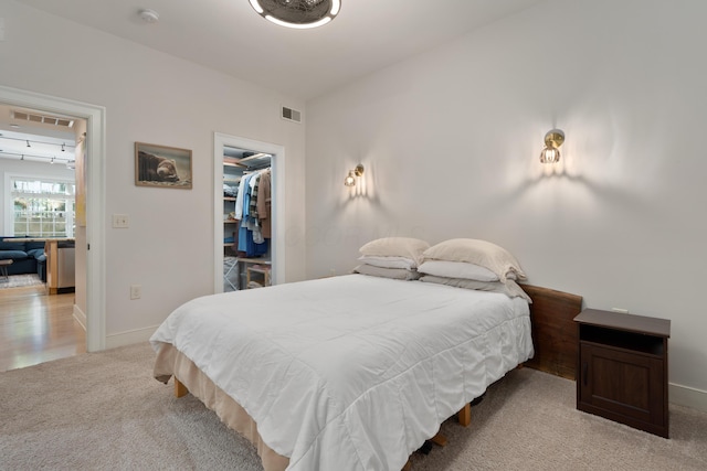 bedroom with visible vents, baseboards, a spacious closet, and light colored carpet