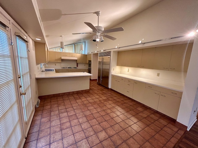 kitchen with a peninsula, a sink, a healthy amount of sunlight, built in fridge, and under cabinet range hood