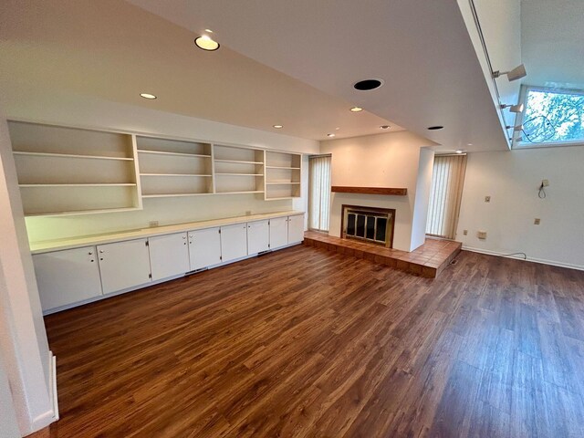 unfurnished living room with baseboards, recessed lighting, dark wood-style flooring, and a tiled fireplace
