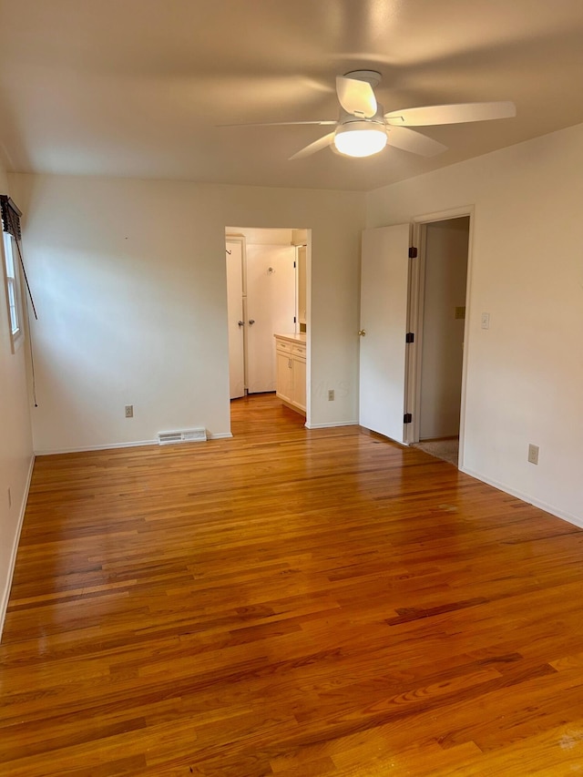 empty room featuring ceiling fan, baseboards, light wood finished floors, and visible vents