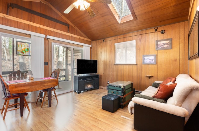 living room featuring lofted ceiling with skylight, ceiling fan, and a healthy amount of sunlight