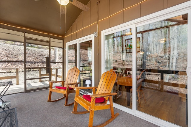sunroom / solarium with a decorative wall, a ceiling fan, lofted ceiling, and carpet floors