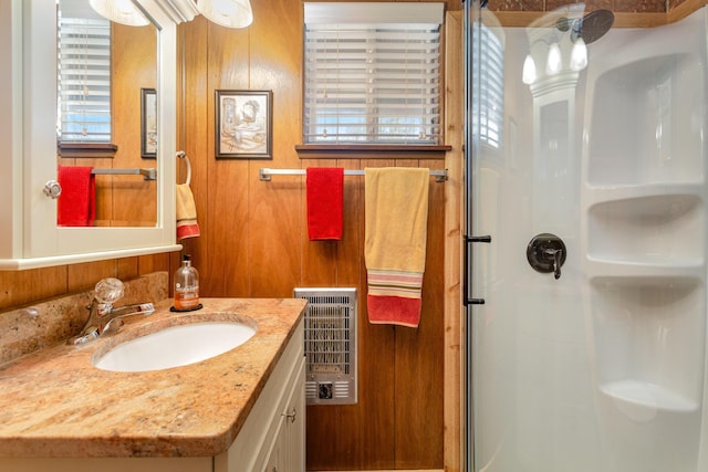 full bathroom with heating unit, vanity, and a stall shower
