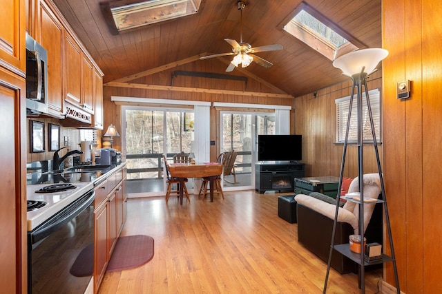 kitchen with electric range, wood ceiling, wood walls, stainless steel microwave, and a sink