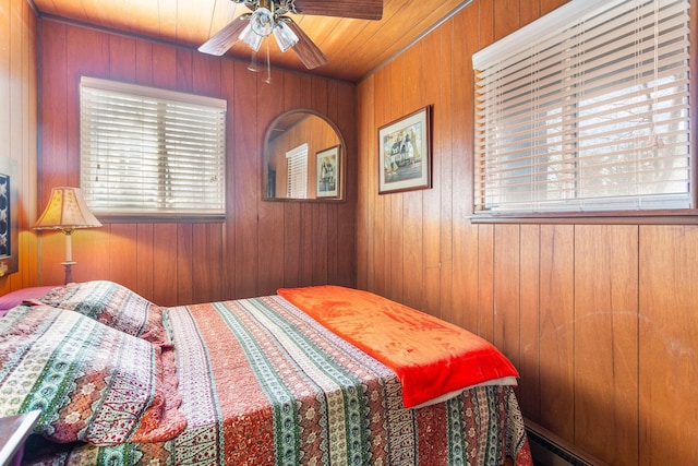 bedroom with wood walls, multiple windows, and ceiling fan