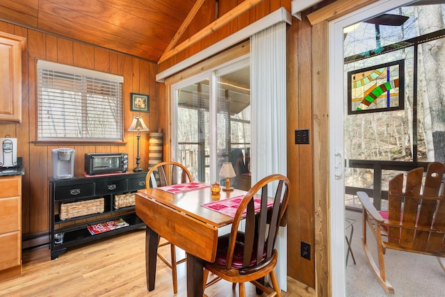 dining room with wooden walls, wooden ceiling, plenty of natural light, and vaulted ceiling