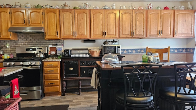 620 Lewis St, Washington Court House, OH 43160 - kitchen with backsplash, light wood-style flooring, appliances with stainless steel finishes, and under cabinet range hood