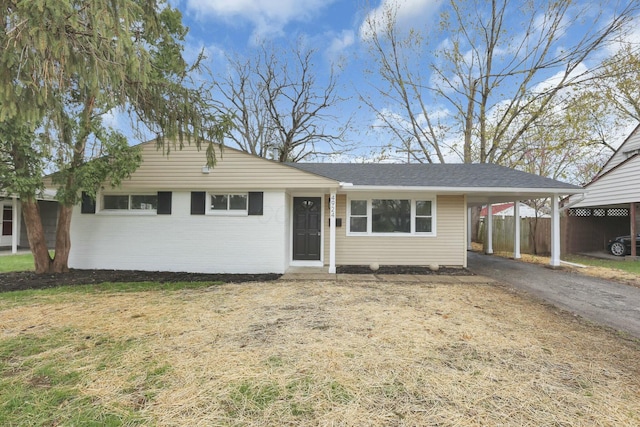 single story home with brick siding, fence, an attached carport, and driveway