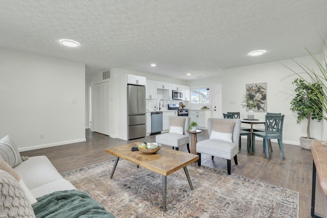 living area with baseboards, recessed lighting, dark wood-style floors, a textured ceiling, and visible vents