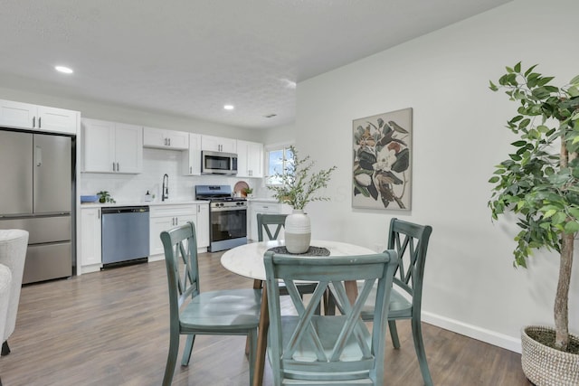 dining room with dark wood-style flooring, baseboards, and recessed lighting