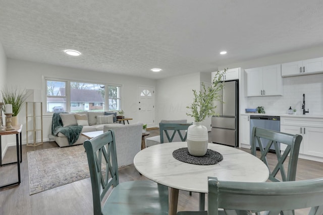 dining area featuring recessed lighting, wood finished floors, and a textured ceiling