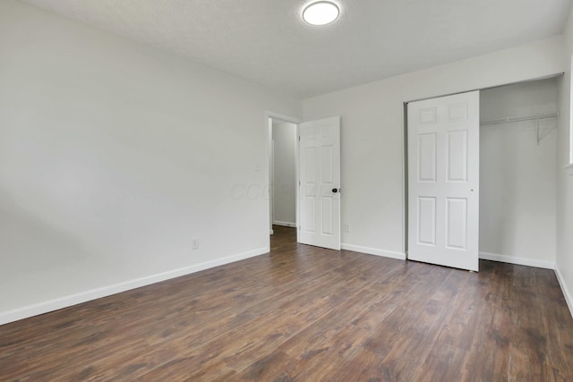 unfurnished bedroom featuring a closet, dark wood-style flooring, and baseboards