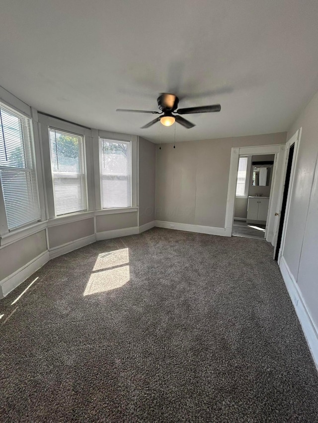 carpeted spare room featuring a wealth of natural light, baseboards, and ceiling fan