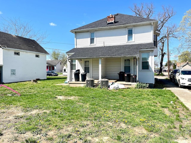 rear view of house featuring a chimney, a shingled roof, covered porch, and a lawn