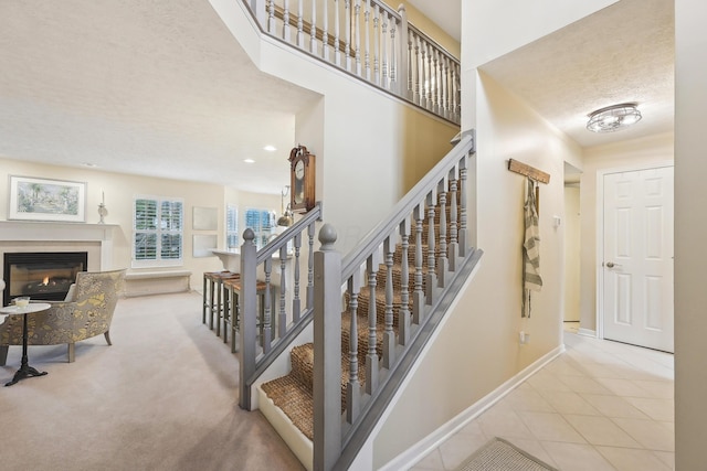 6690 Hermitage Dr, Westerville, OH 43082 - stairway with a glass covered fireplace, a textured ceiling, tile patterned floors, and baseboards