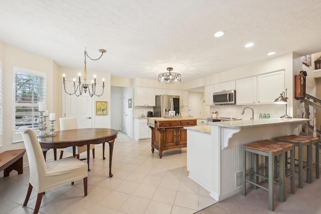6690 Hermitage Dr, Westerville, OH 43082 - kitchen with a peninsula, white cabinetry, a chandelier, and appliances with stainless steel finishes