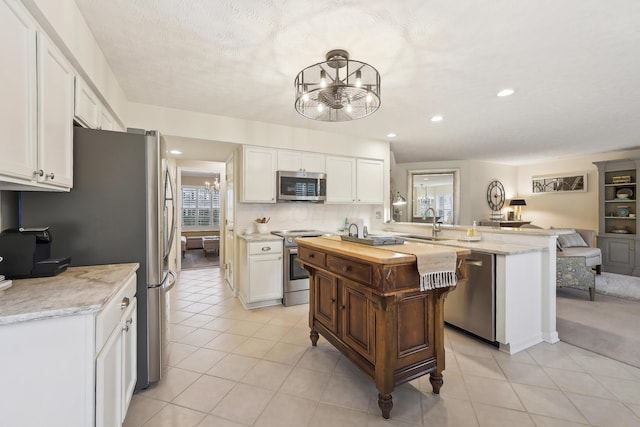 6690 Hermitage Dr, Westerville, OH 43082 - kitchen with a chandelier, appliances with stainless steel finishes, white cabinetry, and a peninsula