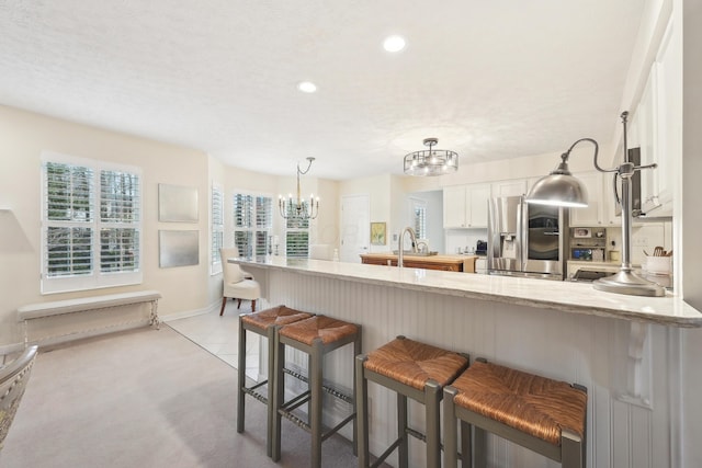 6690 Hermitage Dr, Westerville, OH 43082 - kitchen featuring baseboards, a notable chandelier, white cabinetry, stainless steel refrigerator with ice dispenser, and a breakfast bar area