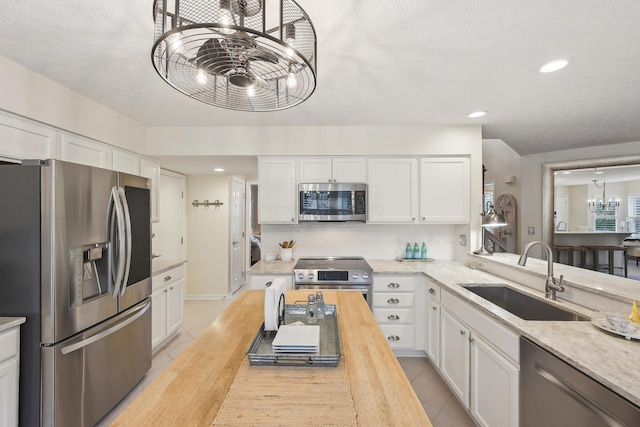 6690 Hermitage Dr, Westerville, OH 43082 - kitchen with stainless steel appliances, a sink, an inviting chandelier, backsplash, and white cabinetry