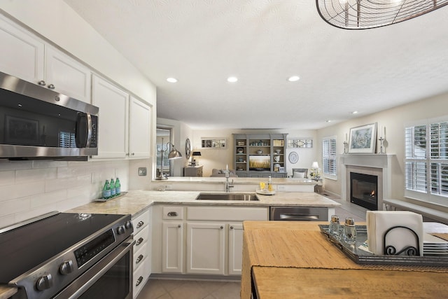 6690 Hermitage Dr, Westerville, OH 43082 - kitchen with white cabinets, a sink, a peninsula, appliances with stainless steel finishes, and open floor plan