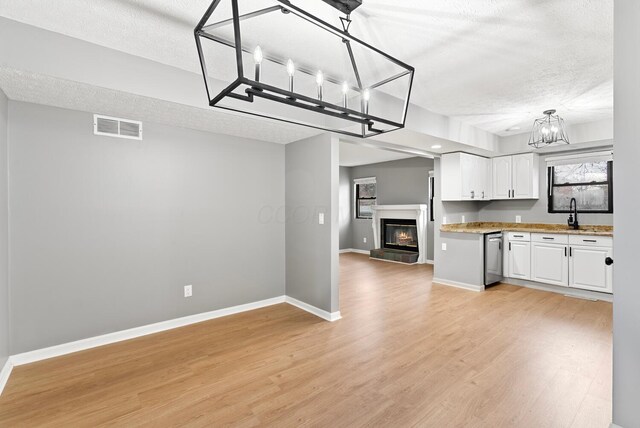 121 Granville St, Pataskala, OH 43062 - kitchen featuring light wood-type flooring, a chandelier, a textured ceiling, white cabinets, and visible vents