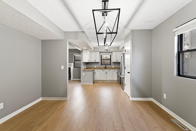 121 Granville St, Pataskala, OH 43062 - kitchen featuring visible vents, baseboards, light wood-type flooring, a chandelier, and white cabinetry