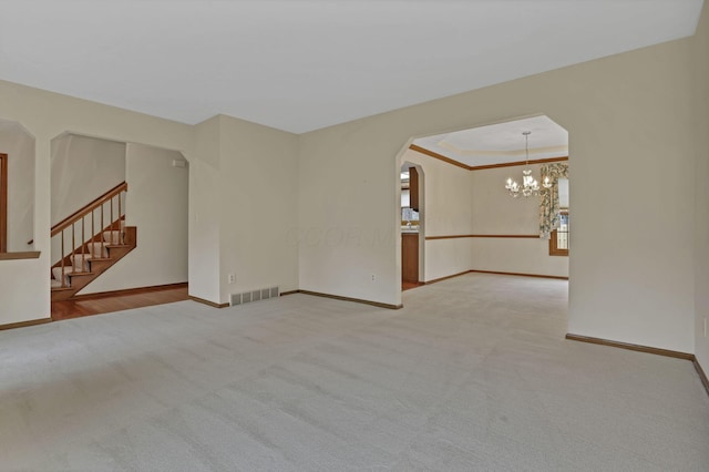 carpeted empty room featuring arched walkways, visible vents, and baseboards