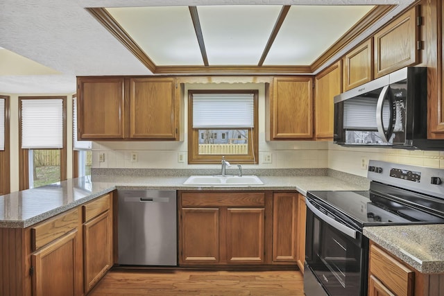 kitchen with stainless steel appliances, a peninsula, a sink, and backsplash