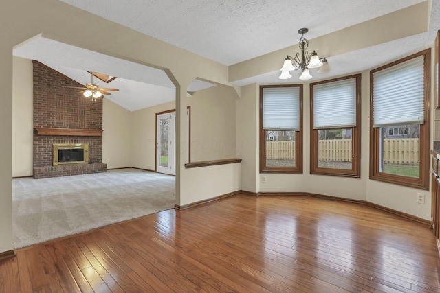 unfurnished living room featuring wood-type flooring, baseboards, a textured ceiling, and ceiling fan with notable chandelier