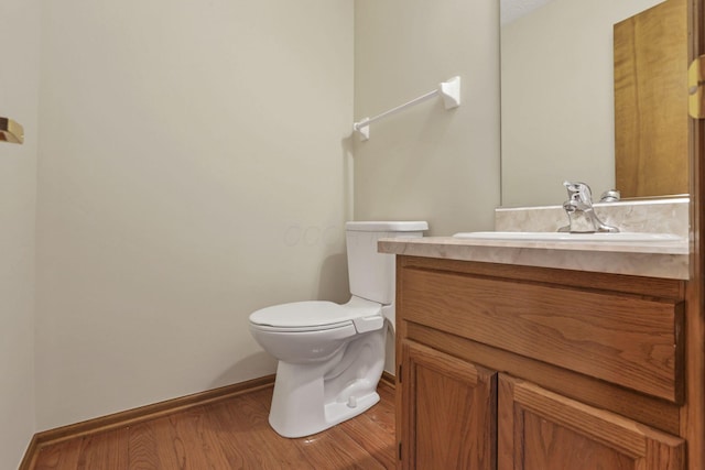 bathroom featuring toilet, wood finished floors, vanity, and baseboards