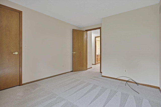 empty room featuring light colored carpet and baseboards
