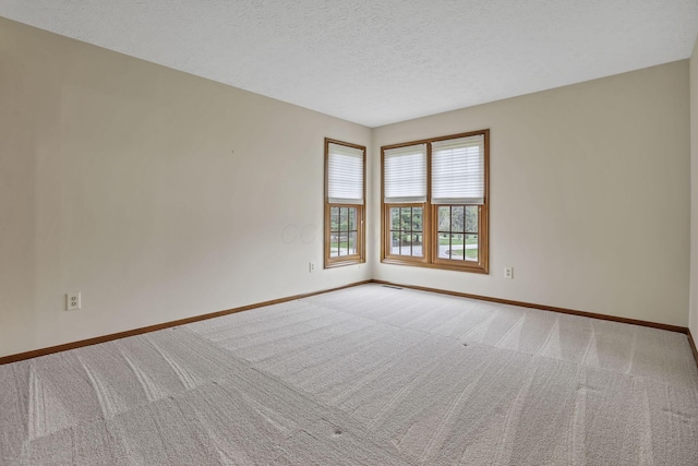empty room with carpet flooring, baseboards, and a textured ceiling