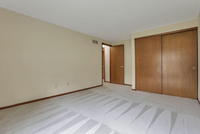 unfurnished bedroom with visible vents, a closet, baseboards, and light carpet