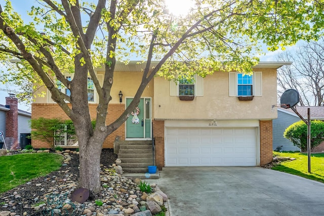 bi-level home with entry steps, stucco siding, an attached garage, concrete driveway, and brick siding