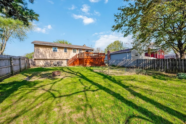 view of yard featuring a wooden deck, a fenced backyard, stairs, and a fire pit